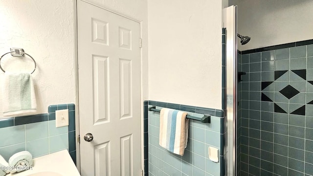 bathroom with tile walls and a shower with shower door