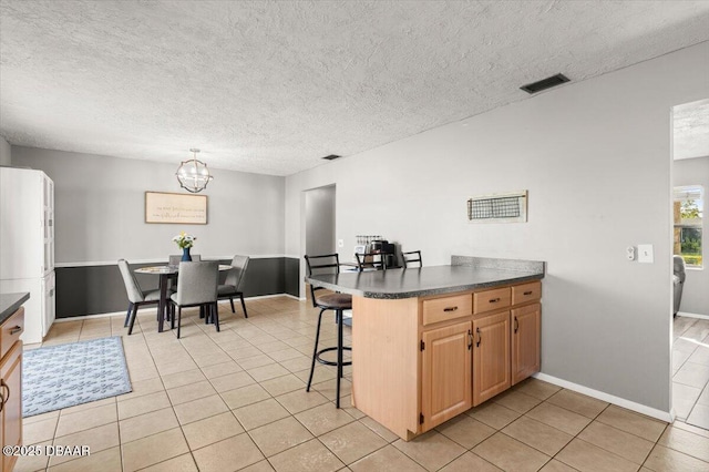 kitchen featuring a chandelier, a textured ceiling, light tile patterned floors, a kitchen breakfast bar, and kitchen peninsula