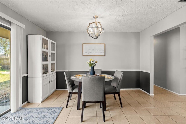 dining room featuring an inviting chandelier, a textured ceiling, and light tile patterned floors