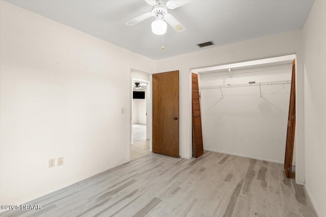 unfurnished bedroom with light hardwood / wood-style flooring, a closet, and ceiling fan