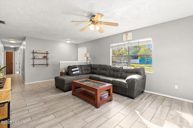 living room featuring ceiling fan, a textured ceiling, and light wood-type flooring