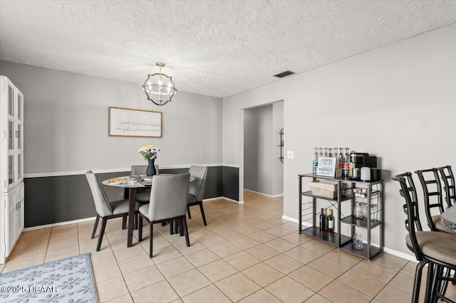 dining space with light tile patterned flooring, a notable chandelier, and a textured ceiling