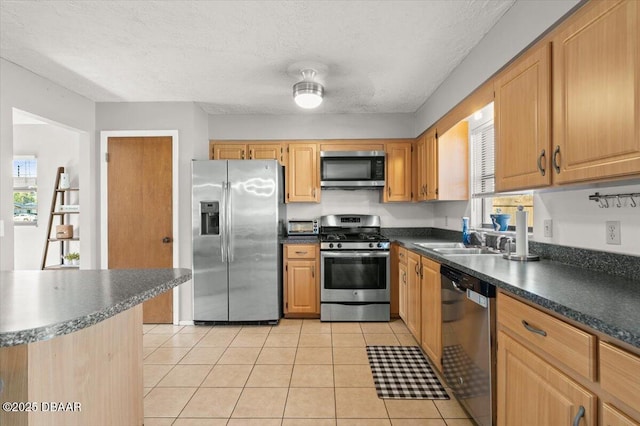 kitchen featuring light tile patterned flooring, stainless steel appliances, sink, and a textured ceiling