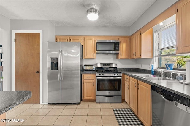 kitchen featuring appliances with stainless steel finishes, sink, a textured ceiling, and light tile patterned floors