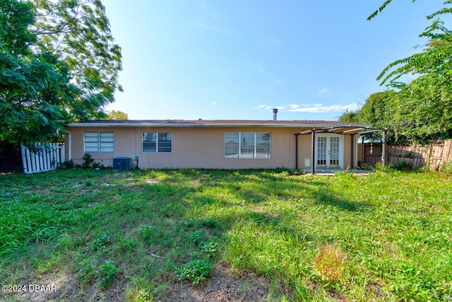 back of property with central AC unit, a lawn, and a patio