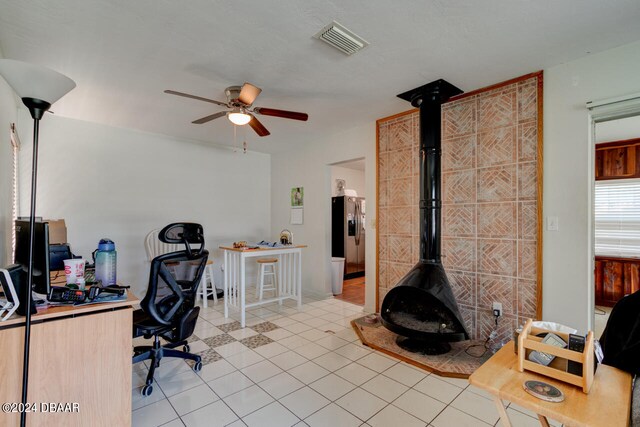 tiled home office with a wood stove and ceiling fan