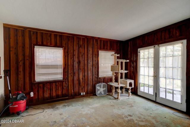 empty room with french doors, light carpet, and wooden walls