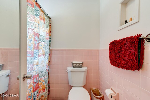 bathroom with tile walls, toilet, and a shower with curtain