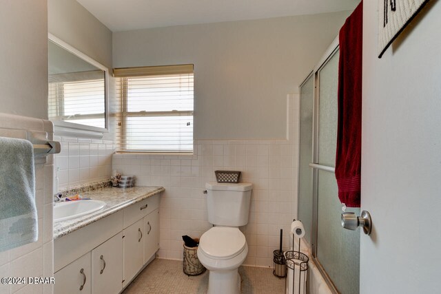 bathroom with walk in shower, tile patterned flooring, vanity, toilet, and tile walls