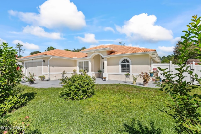 mediterranean / spanish house featuring a garage and a front lawn