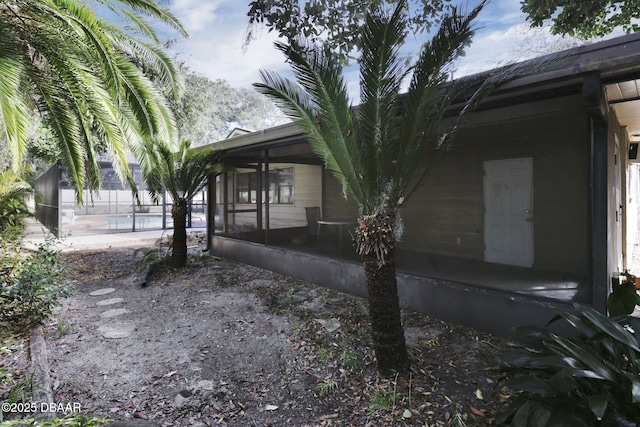 view of side of property with a fenced in pool and a sunroom