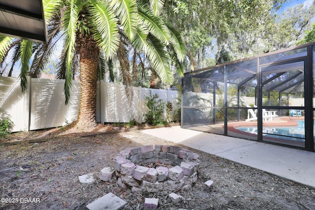 view of yard featuring a fire pit, a fenced in pool, a lanai, and a patio area