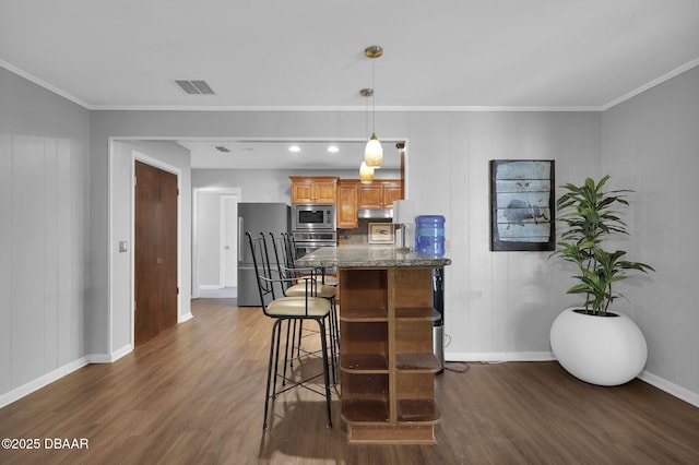 kitchen featuring appliances with stainless steel finishes, a kitchen breakfast bar, dark hardwood / wood-style flooring, decorative light fixtures, and dark stone counters