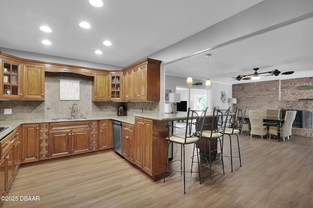 kitchen featuring sink, a breakfast bar, hanging light fixtures, light stone countertops, and kitchen peninsula