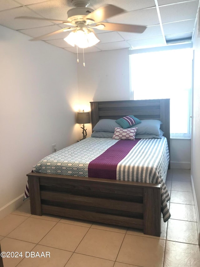 tiled bedroom with a paneled ceiling and ceiling fan