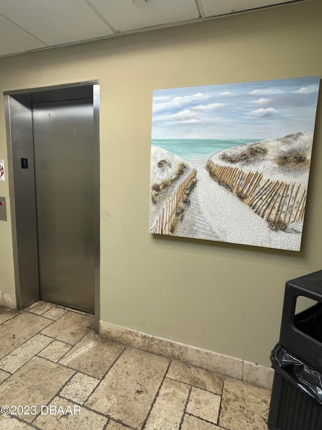 interior details with elevator and a paneled ceiling