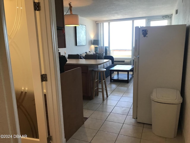 3501 S Atlantic Ave Unit 2050, Daytona Beach, FL 32118 - kitchen with freestanding refrigerator, a kitchen bar, light tile patterned flooring, and plenty of natural light