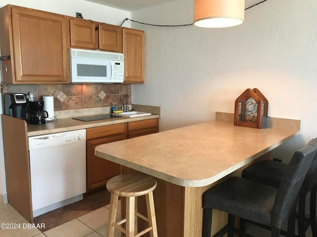 kitchen featuring white appliances, a breakfast bar area, backsplash, and kitchen peninsula