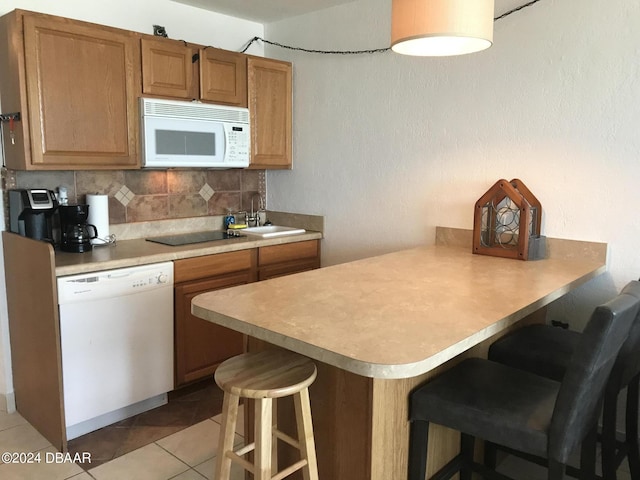 3501 S Atlantic Ave Unit 2050, Daytona Beach, FL 32118 - kitchen featuring white appliances, a kitchen bar, a peninsula, decorative backsplash, and brown cabinets