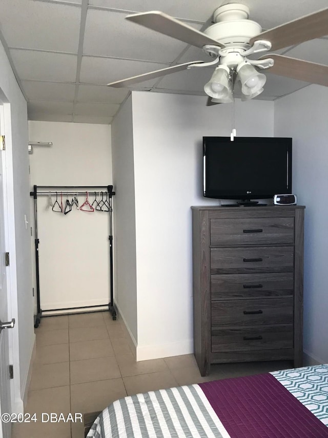 unfurnished bedroom with ceiling fan, tile patterned floors, and a drop ceiling