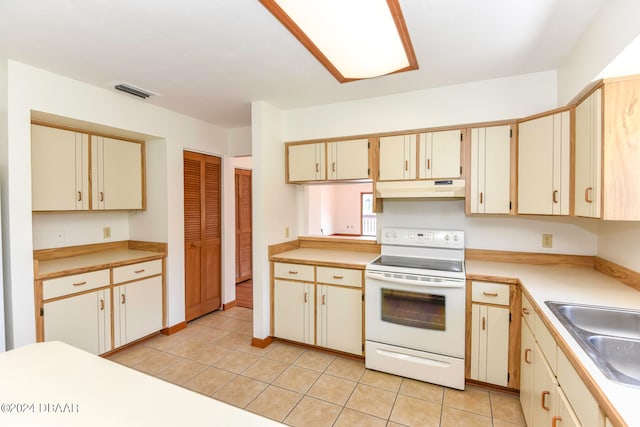 kitchen with sink, cream cabinets, light tile patterned flooring, and white electric range oven