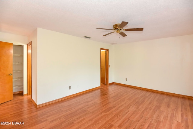 spare room with a textured ceiling, light hardwood / wood-style flooring, and ceiling fan