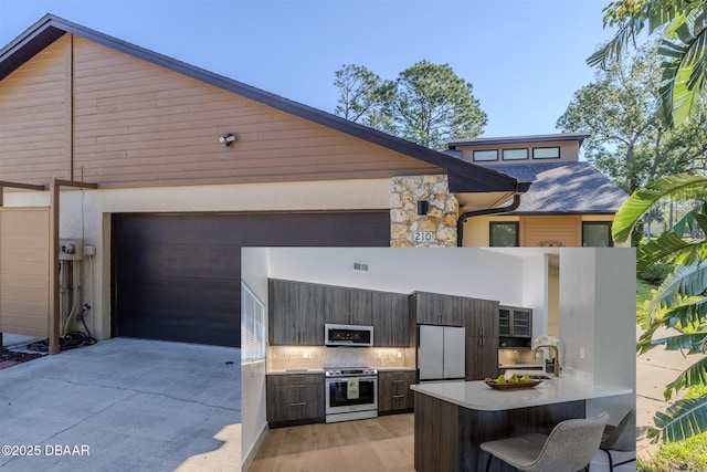 exterior space featuring stone siding, exterior kitchen, and concrete driveway