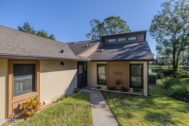 view of front of home featuring stucco siding, a front yard, and roof with shingles