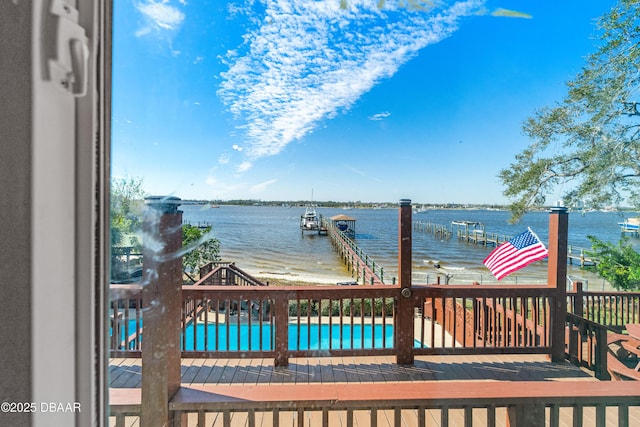 wooden deck with a water view, a boat dock, and a community pool