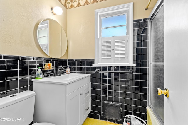 full bathroom featuring enclosed tub / shower combo, vanity, toilet, and tile walls