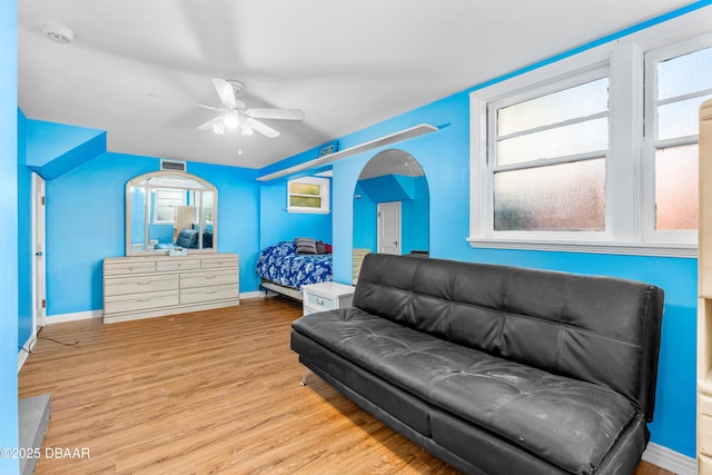 bedroom with baseboards, arched walkways, and light wood-style flooring