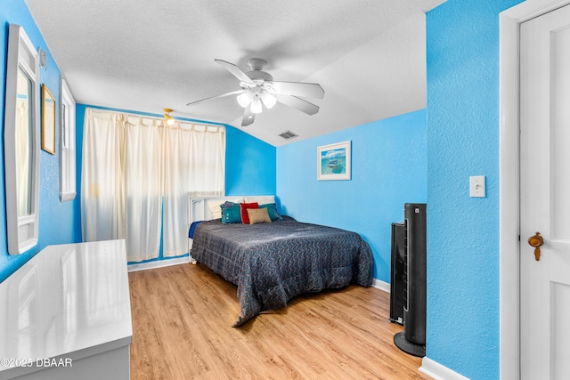 bedroom with visible vents, lofted ceiling, a textured ceiling, and wood finished floors