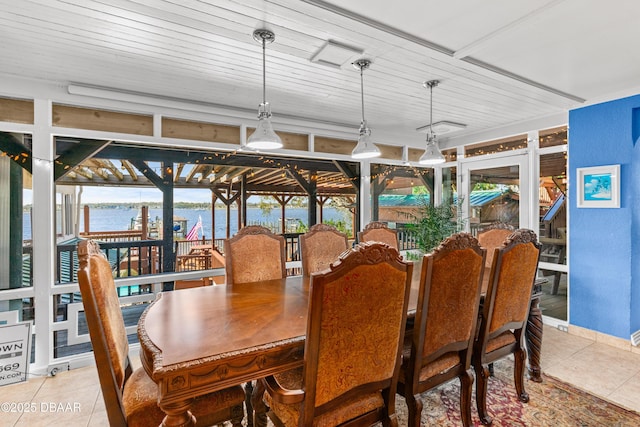 dining space with light tile patterned floors and a water view