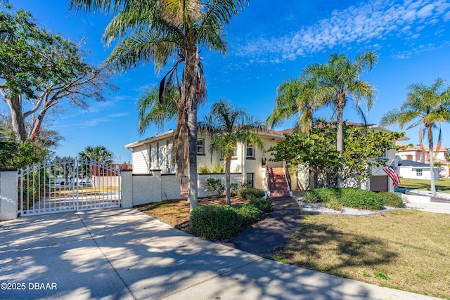 view of front of property featuring stucco siding, fence, concrete driveway, and a gate