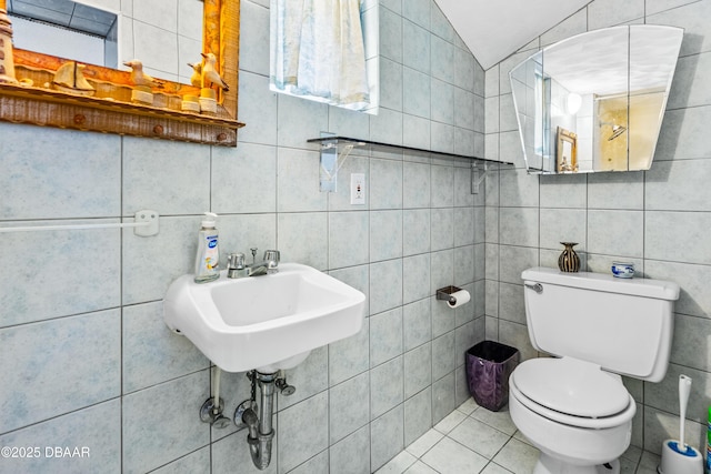 bathroom featuring tile patterned flooring, vaulted ceiling, tile walls, and toilet