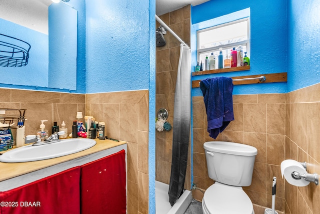 bathroom with toilet, tile walls, vanity, and a shower with shower curtain