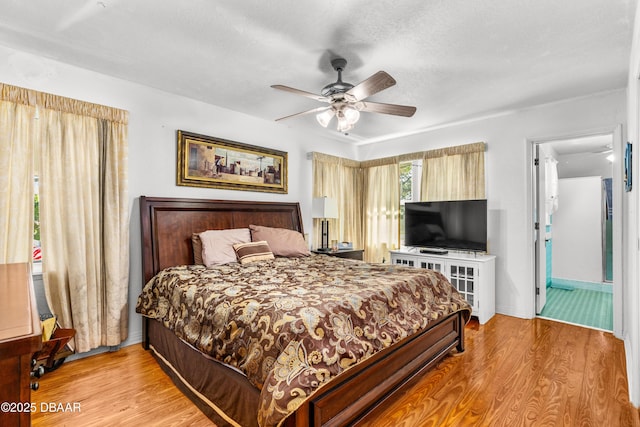 bedroom with a textured ceiling, baseboards, a ceiling fan, and wood finished floors