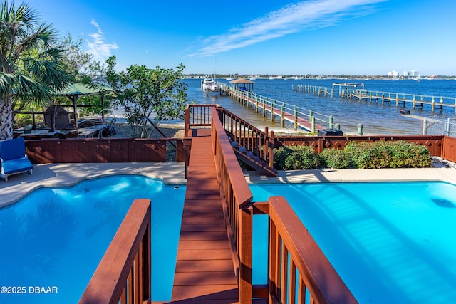 view of pool featuring a fenced in pool, a water view, and a boat dock