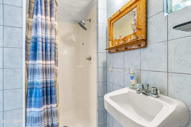 bathroom with tile walls, a stall shower, and a sink