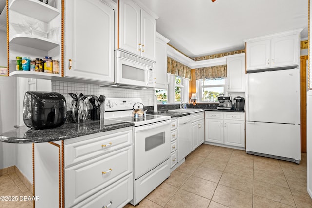 kitchen with light tile patterned flooring, sink, white cabinetry, white appliances, and dark stone counters