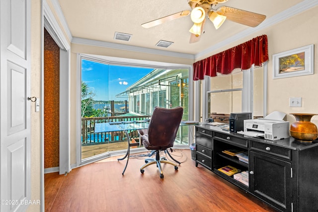 office area with a ceiling fan, wood finished floors, visible vents, and ornamental molding