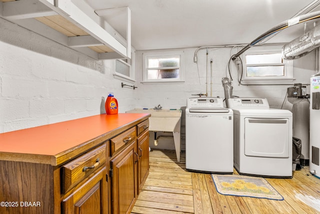 clothes washing area featuring light wood-style flooring, cabinet space, independent washer and dryer, and a sink