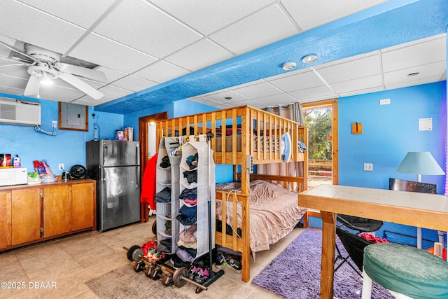 bedroom with electric panel, a drop ceiling, and freestanding refrigerator