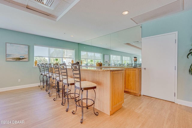 kitchen with light stone countertops, kitchen peninsula, a breakfast bar area, and light hardwood / wood-style flooring