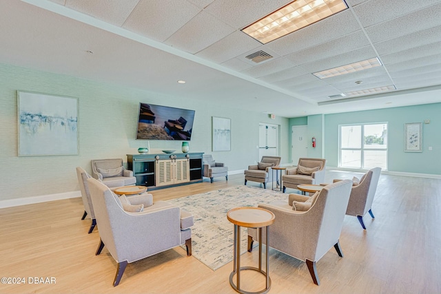 living room with light hardwood / wood-style flooring and a drop ceiling