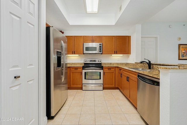 kitchen with sink, light stone countertops, stainless steel appliances, and light tile patterned floors