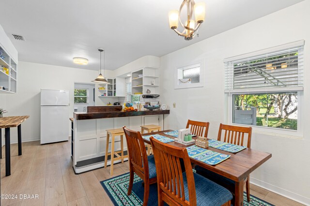 dining space with light hardwood / wood-style floors and an inviting chandelier