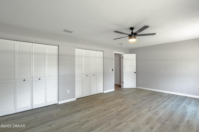 131 Lake Charles Rd, Deland, FL 32724 - unfurnished bedroom featuring two closets, wood finished floors, a textured ceiling, baseboards, and a ceiling fan