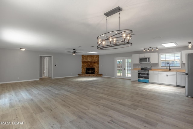 131 Lake Charles Rd, Deland, FL 32724 - unfurnished living room featuring a chandelier, a ceiling fan, plenty of natural light, and a large fireplace