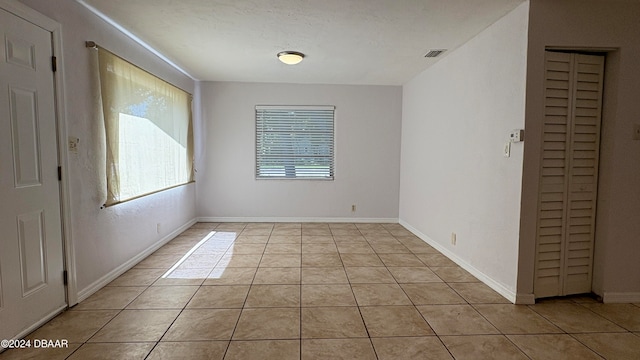 tiled empty room featuring a textured ceiling